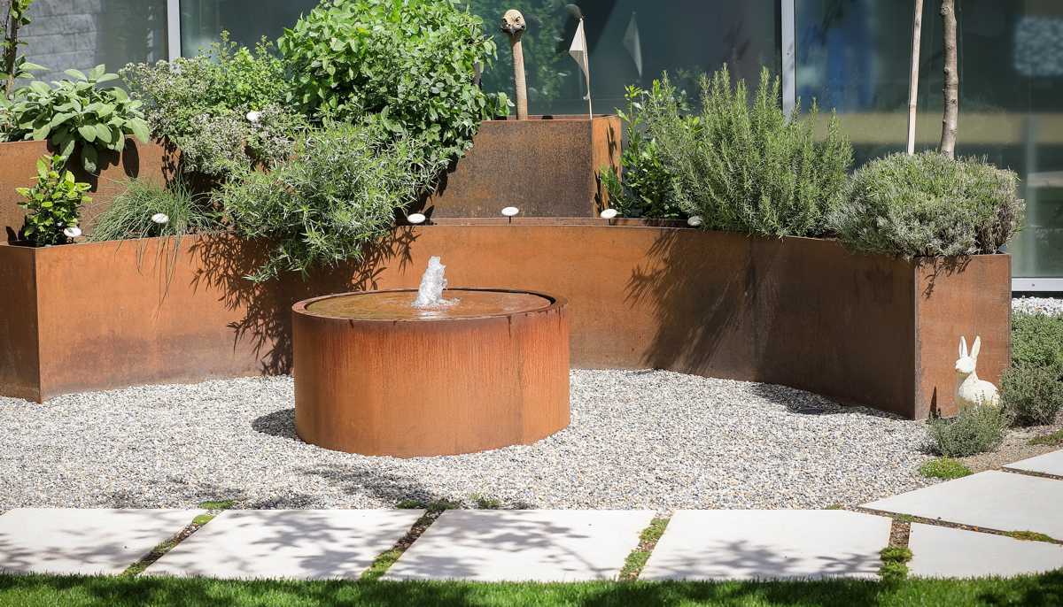 Cortenstahl Brunnen AQUA CUBUS rund mit Rand in Kombination mit gebogenen Pflanztrögen